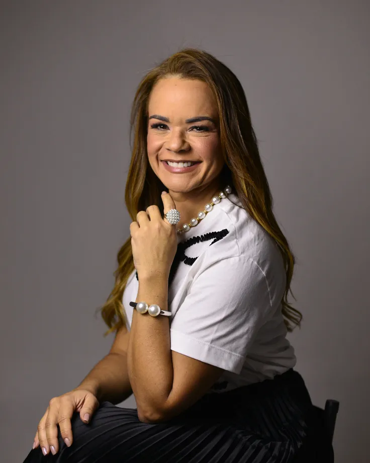 Dra. Milena Paiva sorrindo, sentada, de blusa branca